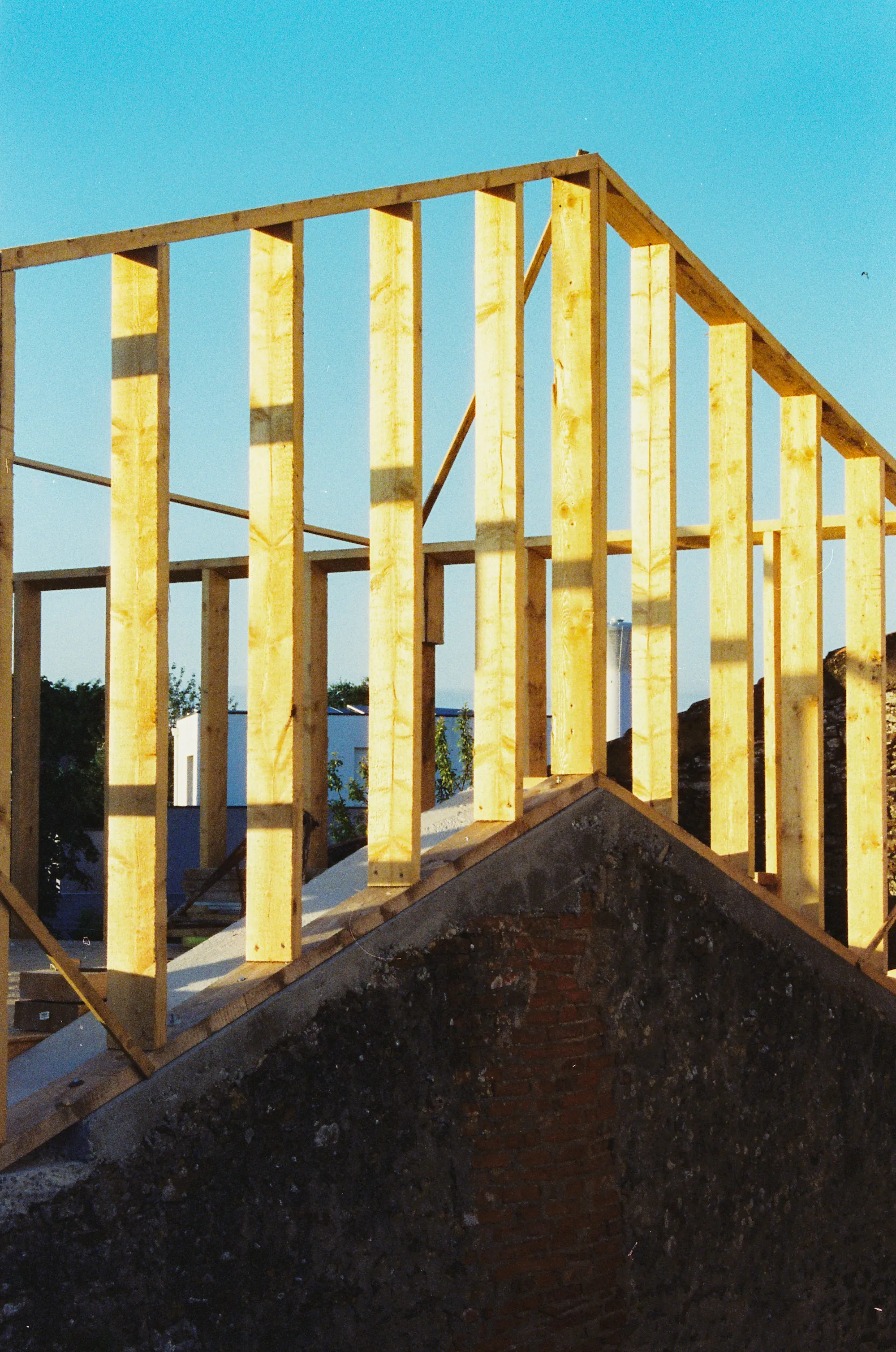 New wall framing rising above an older stone gable