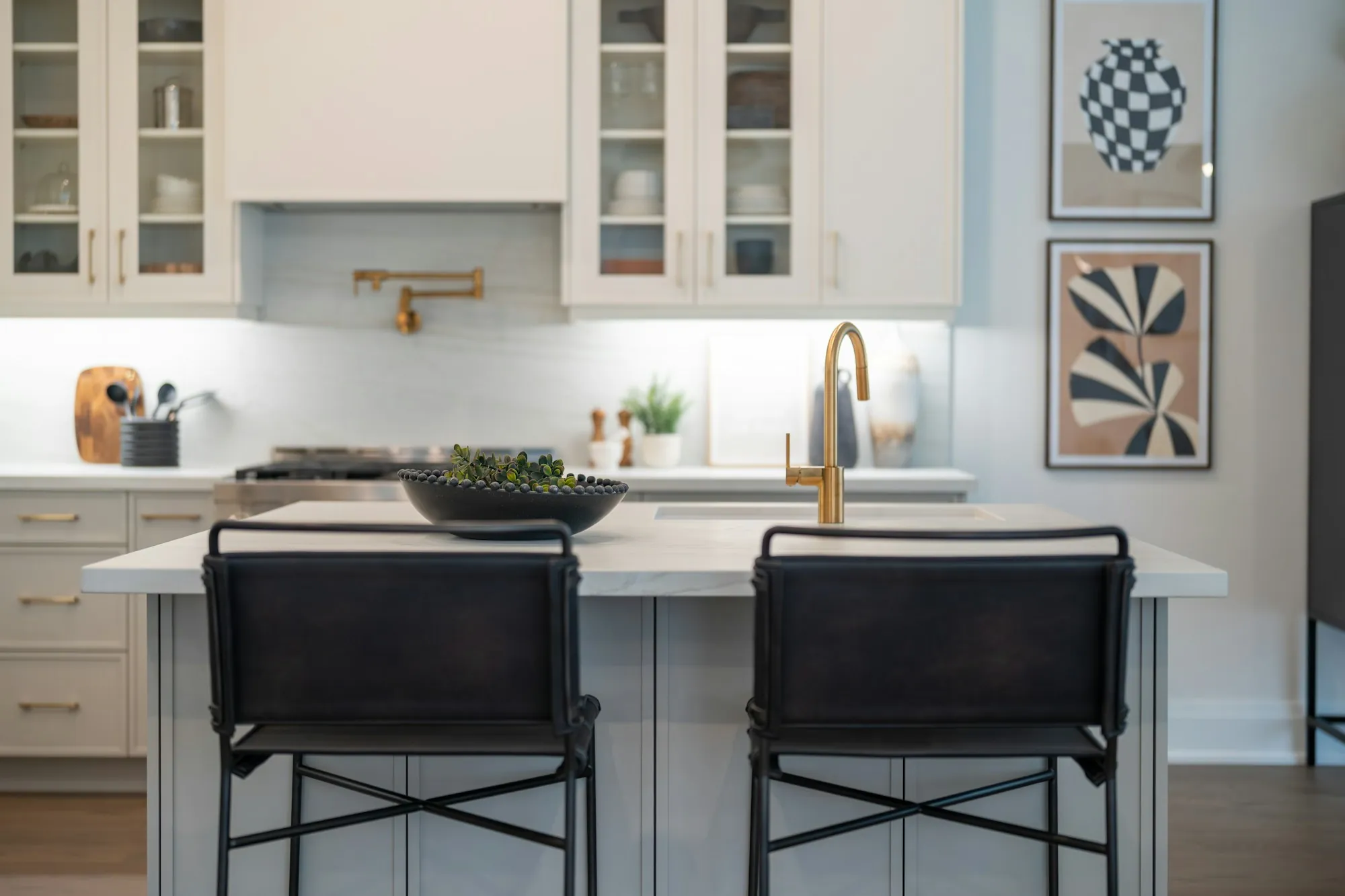 Kitchen island with a brass faucet and two counter stools